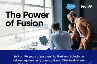 A group of business professionals discussing at a table, with a laptop open, surrounded by notes.