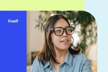 Person wearing glasses and a denim shirt, smiling with plant background.